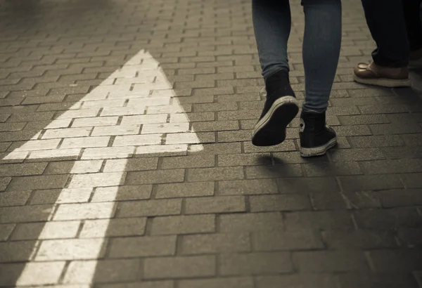 Arrow straight on street with walking people — Stock Photo, Image