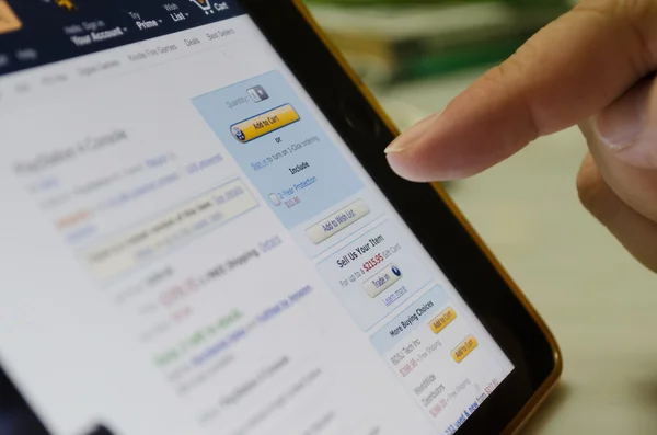 Bangkok, Thailand - 17 juni 2015: Oidentifierade mänskliga finger touch på skärmen på tablett enhet på ' Lägg till butik på Amazon, största kända online shopping webbplats, att köpa någon produkt