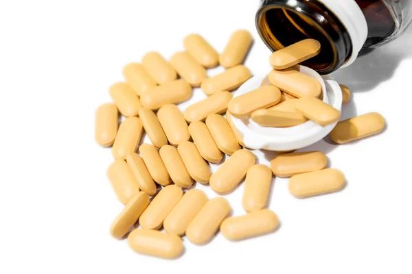 Yellow Vitamin tablet poured from brown bottle isolated — Stock Photo, Image