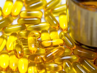 Balık yağı kapsülleri ve kahverengi şişe yığınları 