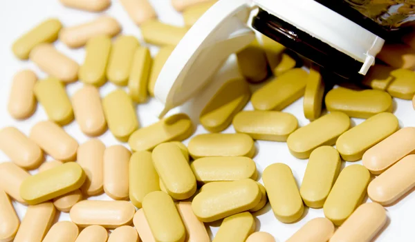 Multivitaminico versato da bottiglia marrone isolato — Foto Stock