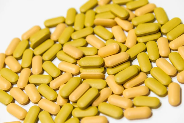 Кучи желтых и оранжевых мульти-витаминов таблетки изолированы — стоковое фото