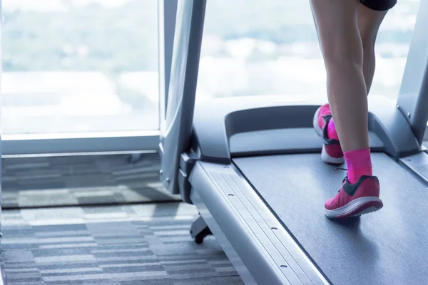 在跑步机上的粉红色鞋子的陌生的女人 图库照片