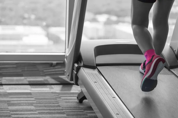 未知的女人穿粉红色的鞋子在拆分色调的跑步机上运行 免版税图库图片