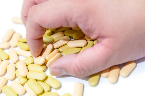 Mano umana afferrare pillole vitaminiche sopra bianco — Foto Stock