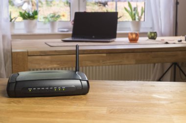 Kablosuz modem modem modem ağ merkezi ahşap bir masada. Arka planda dizüstü veya dizüstü bilgisayar ile.