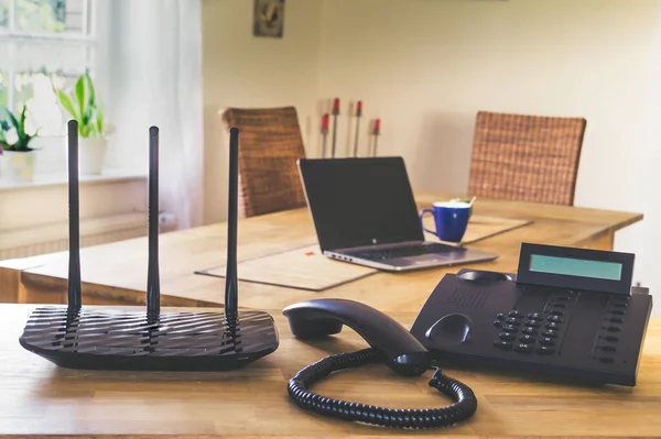 Siyah telefon ve ahşap masadaki siyah kablosuz ağ yönlendirici. Merkez ofis kavramı.