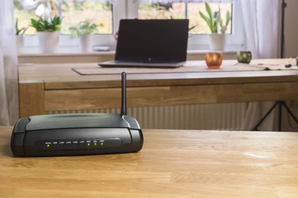 Kablosuz modem modem modem ağ merkezi ahşap bir masada. Arka planda dizüstü veya dizüstü bilgisayar ile.