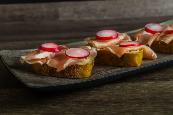 Parma jambonlu ve ahşap tabakta servis edilen taze turplu lezzetli ekmek sandviçi..