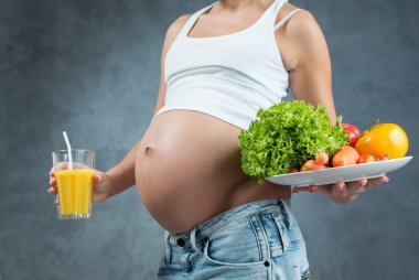 Close up of a cute pregnant belly tummy and healthy food. Pregna