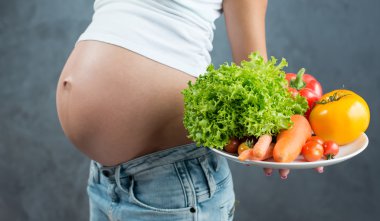 Close up of a cute pregnant belly tummy and healthy food. Pregna