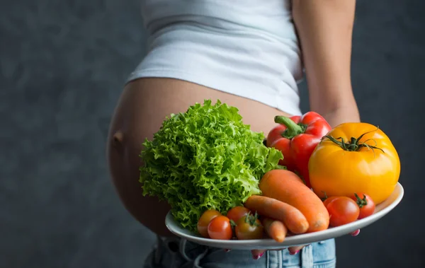 Primer plano de una linda barriga embarazada y comida saludable. Pregna. —  Fotos de Stock