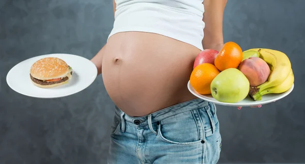 Primer plano de una linda barriga embarazada y comida saludable. Pregna. —  Fotos de Stock