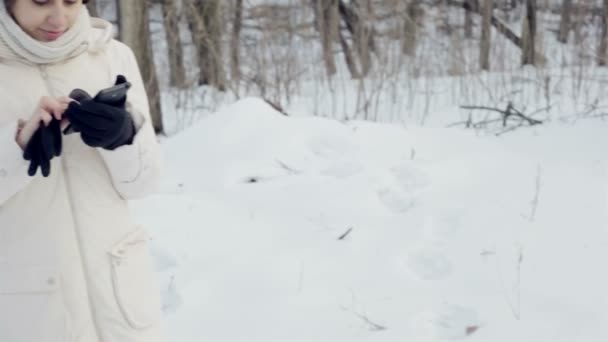 Schönes Mädchen, das im Winterpark mit dem Smartphone spricht — Stockvideo