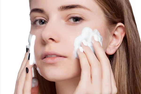 Hermosa cara de limpieza mujer con tratamiento de espuma fondo de luz — Foto de Stock