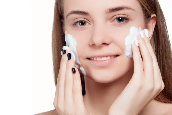 Mulher bonita limpeza rosto com tratamento de espuma luz de fundo — Fotografia de Stock