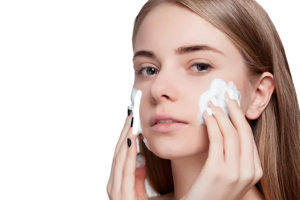 Красивая женщина чистит лицо с помощью пенопласта легкий фон — стоковое фото
