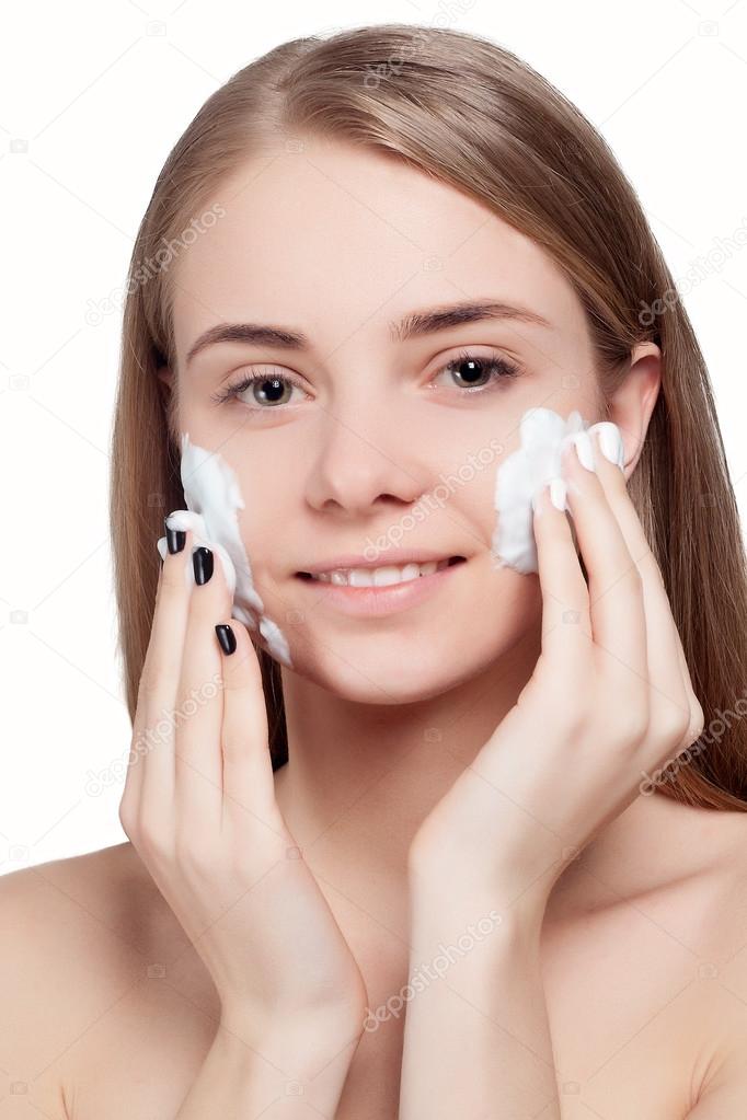 Beautiful woman cleaning face with foam treatment light background