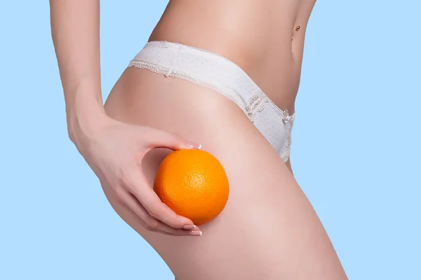 Hermosa figura femenina con una naranja sostiene cerca del culo —  Fotos de Stock