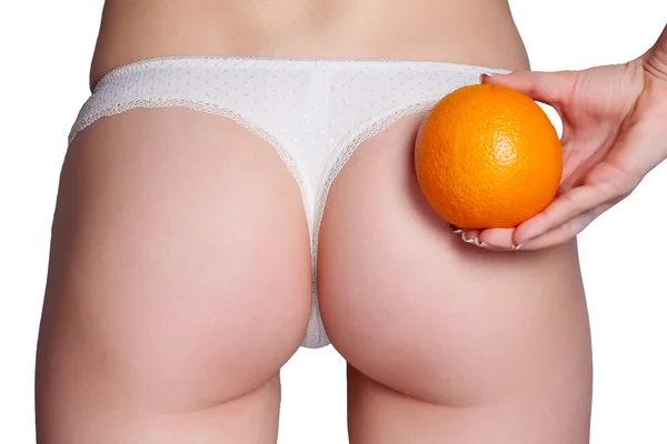 Hermosa figura femenina con una naranja sostiene cerca del culo — Foto de Stock