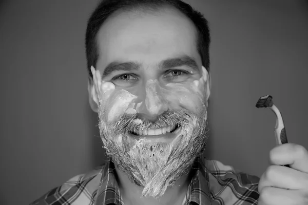 Красивый мужчина с пеной для бритья на лице и бритвой — стоковое фото