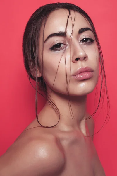 Schöne junge Frau posiert auf rosa glänzenden Hintergrund — Stockfoto