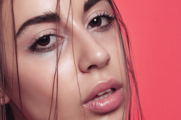 Beautiful young woman posing on pink shiny background