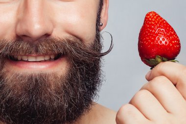 çilek tutarak ve gülümseyen yakın çekim portre genç adam