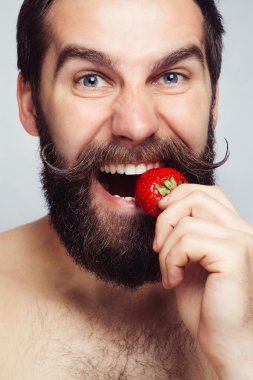 çilek tutarak ve gülümseyen yakın çekim portre genç adam