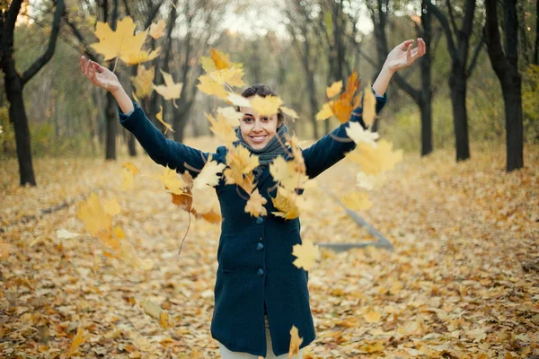 Frau wirft gelbe Blätter in die Luft — Stockfoto