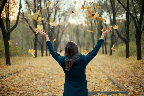 Mulher jogando folhas amarelas no ar — Fotografia de Stock