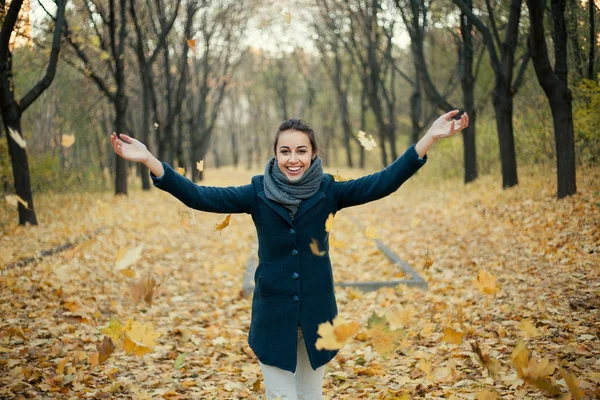 Vrouw gele bladeren in de lucht gooien — Stockfoto