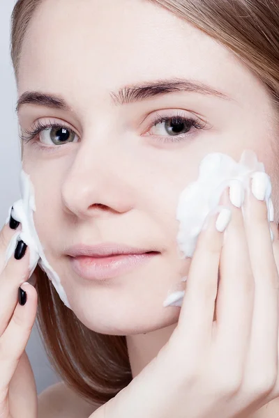 Close-up mulher limpa espuma de pele no fundo cinza — Fotografia de Stock