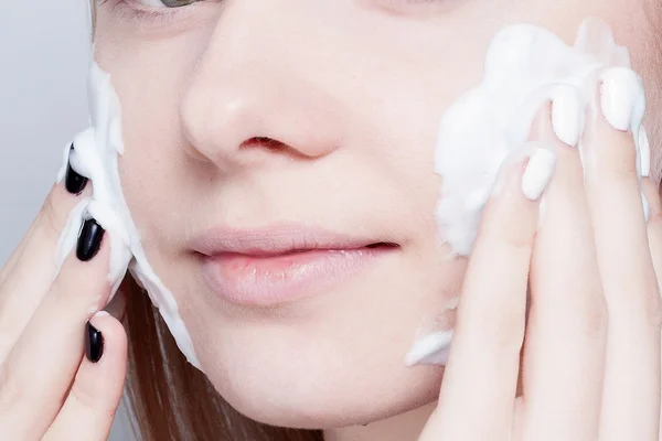 La mujer de cerca limpia la espuma de la piel sobre el fondo gris —  Fotos de Stock