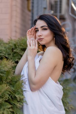 İnsanlar, dinlenme, rahatlık ve rahatlık konsepti. Akşam sokaklarında battaniyeye sarılmış genç bir kadın. Genç bir kadının portresi şafak vakti eski bir binada duruyor.