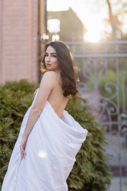 İnsanlar, dinlenme, rahatlık ve rahatlık konsepti. Akşam sokaklarında battaniyeye sarılmış genç bir kadın. Genç bir kadının portresi şafak vakti eski bir binada duruyor.