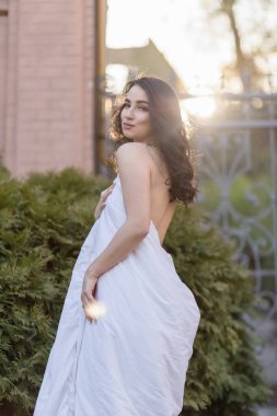 İnsanlar, dinlenme, rahatlık ve rahatlık konsepti. Akşam sokaklarında battaniyeye sarılmış genç bir kadın. Genç bir kadının portresi şafak vakti eski bir binada duruyor.