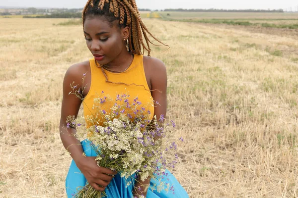 アフリカ系アメリカ人の若い女性が外で楽しんでる 現場で笑う少女 野生の花の花束 美しい若いアフリカ系アメリカ人女性 — ストック写真