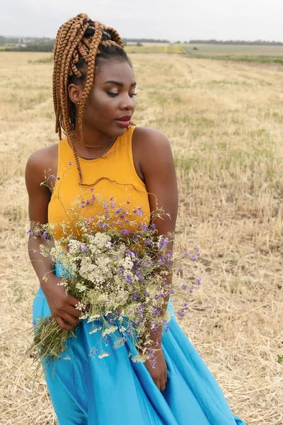 アフリカ系アメリカ人の若い女性が外で楽しんでる 現場で笑う少女 野生の花の花束 美しい若いアフリカ系アメリカ人女性 — ストック写真