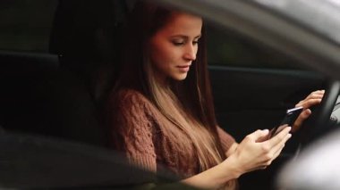 transport, vehicle and technology concept - smiling woman in car using smartphone. corresponding with colleagues using a smartphone. 4k