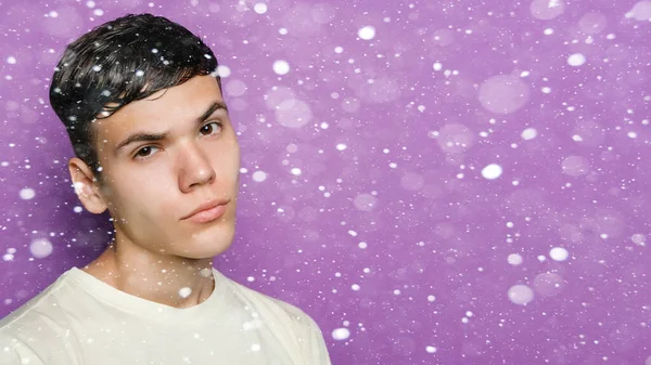 snow, winter, christmas, people, beauty concept - Indoor shot of handsome guy with brooding expression, stands against purple background, free space aside. People and emotions. 16: 9 panoramic format.
