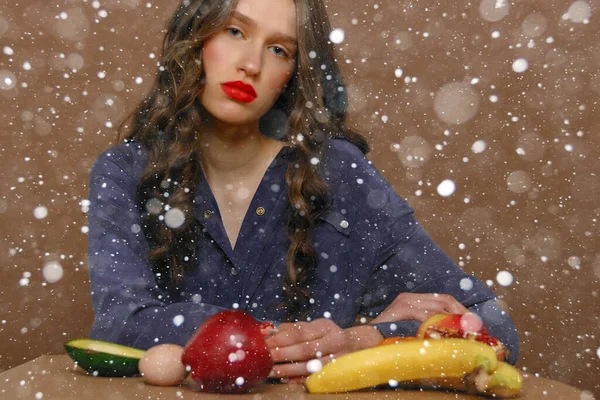 snow, winter, christmas, people, beauty concept - Young woman in group of fruit. Healthcare and healthy nutrition concept. Red lipstick. 16:9 panoramic format.