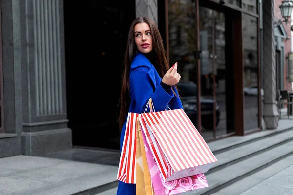 一个漂亮的年轻时尚女性 带着购物袋站在商店橱窗边 一边喊着智能手机 一边说话 购物女人好玩的电话 — 图库照片