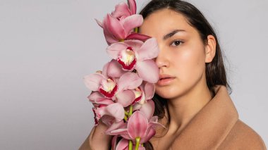 Gri arka planda stüdyoda poz veren kahverengi ceketli baştan çıkarıcı sarışın kadın. Pastel gündelik bahar kıyafetleri içinde zarif bir model. Sağlıklı ciltli ve dallı güzel bir kız. 16: 9 panoramik biçimi.