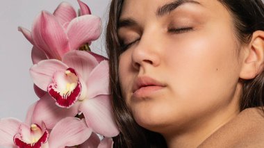 Gri arka planda stüdyoda poz veren kahverengi ceketli baştan çıkarıcı sarışın kadın. Pastel gündelik bahar kıyafetleri içinde zarif bir model. Sağlıklı ciltli ve dallı güzel bir kız. 16: 9 panoramik biçimi.