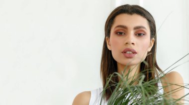 Güzel melez bir kadının yakın plan portresi. Kameraya bakan Afrikalı bir kadının portresi. Kız ve palmiye dalı.