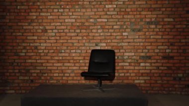 Yeni Siyah Deri Ofis Patronu Sandalyesi ve tuğla duvara dayalı küçük bir sahne. Hoparlörler için yer. Boş yer. Yeni Şık Ofis Mobilyaları