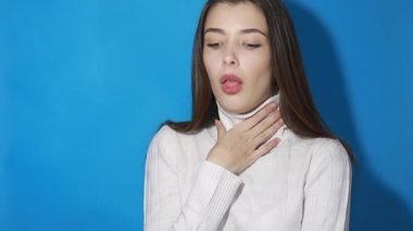 Boğazı ağrıyan, nefes nefese kalan boyun, gırtlak iltihabı olan solunum enfeksiyonu, grip belirtileri, bademcik iltihabı ya da tiroid bozuklukları olan bir kız. Stüdyo çekimi mavi arkaplanda izole edildi