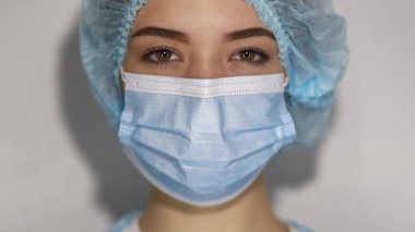 Üzgün ve yorgun doktor gözlerini açar ve kameraya bakar. Tıbbi malzeme portresi. Yakın plan. Koruyucu Yüz Maskeli Kadın,