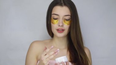 Güzellik, insanlar ve sağlık konsepti. Harika esmer bir kadının çıplak portresi. Daha iyi ve taze görünmek için gözlerinin altına altın bantlar takıyor. Güzel model kız kameraya gülümsüyor..